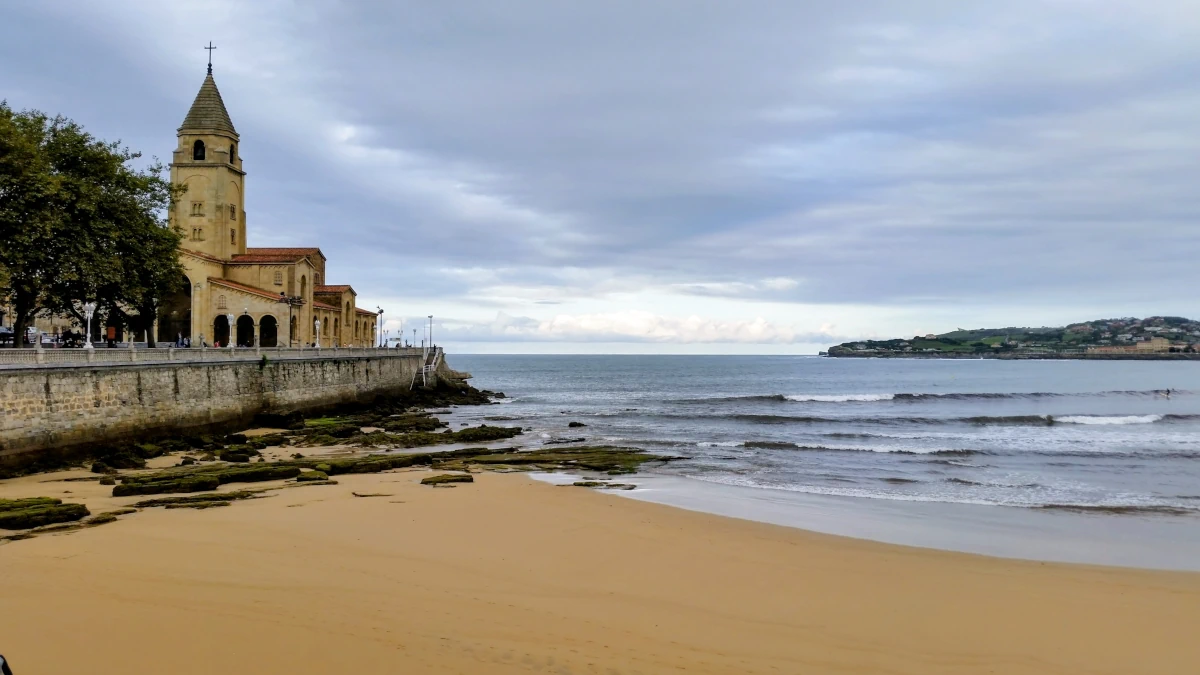 Plaża San Lorenzo w Gijón z widokiem na Morze Kantabryjskie i zabudowę miasta
