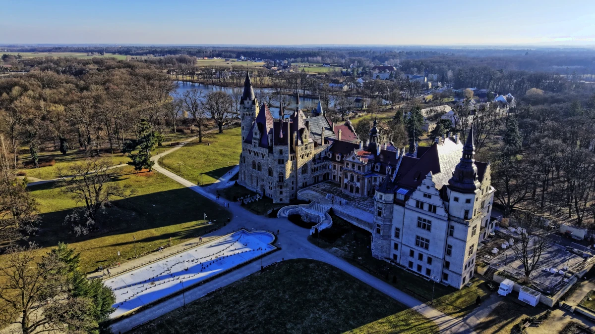 Zamek w Mosznej – panorama rezydencji z widocznymi wieżami i otaczającą zielenią