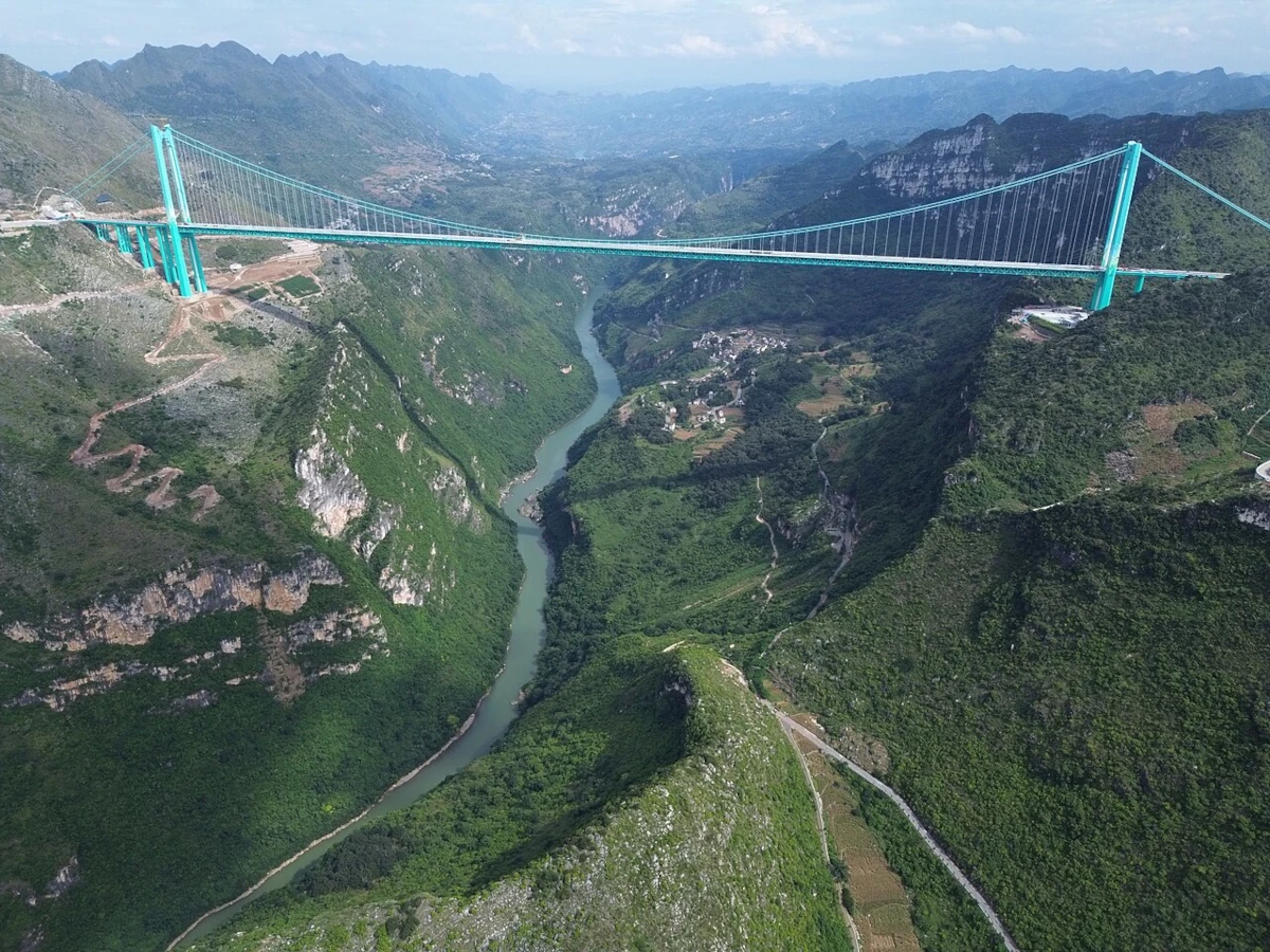 Most Huajiang Canyon Bridge rozpięty nad głębokim kanionem w górzystym krajobrazie Chin
