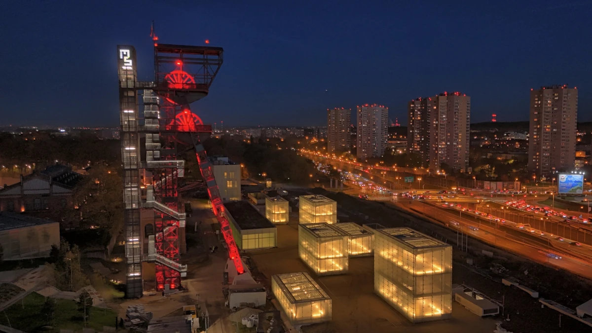 Muzeum Śląskie w Katowicach nocą – szklane kubiki ekspozycyjne i podświetlona wieża szybu kopalnianego na tle miasta
