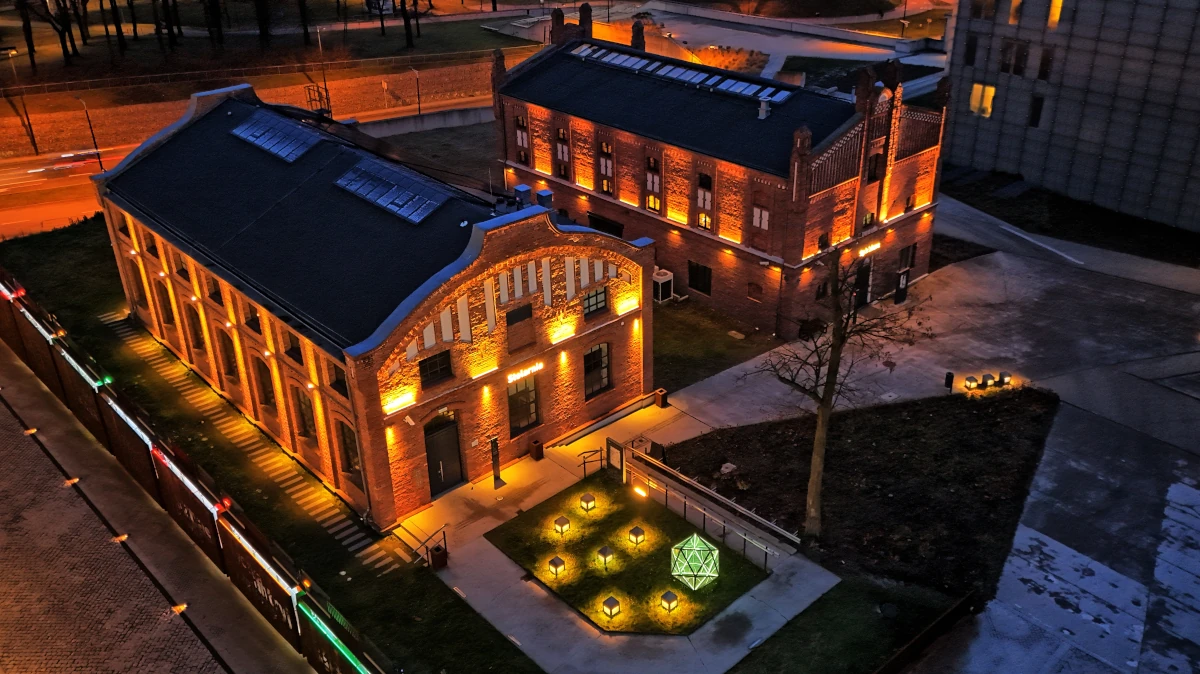 Zabytkowe budynki dawnej kopalni na terenie Muzeum Śląskiego w Katowicach nocą, podświetlona ceglana architektura