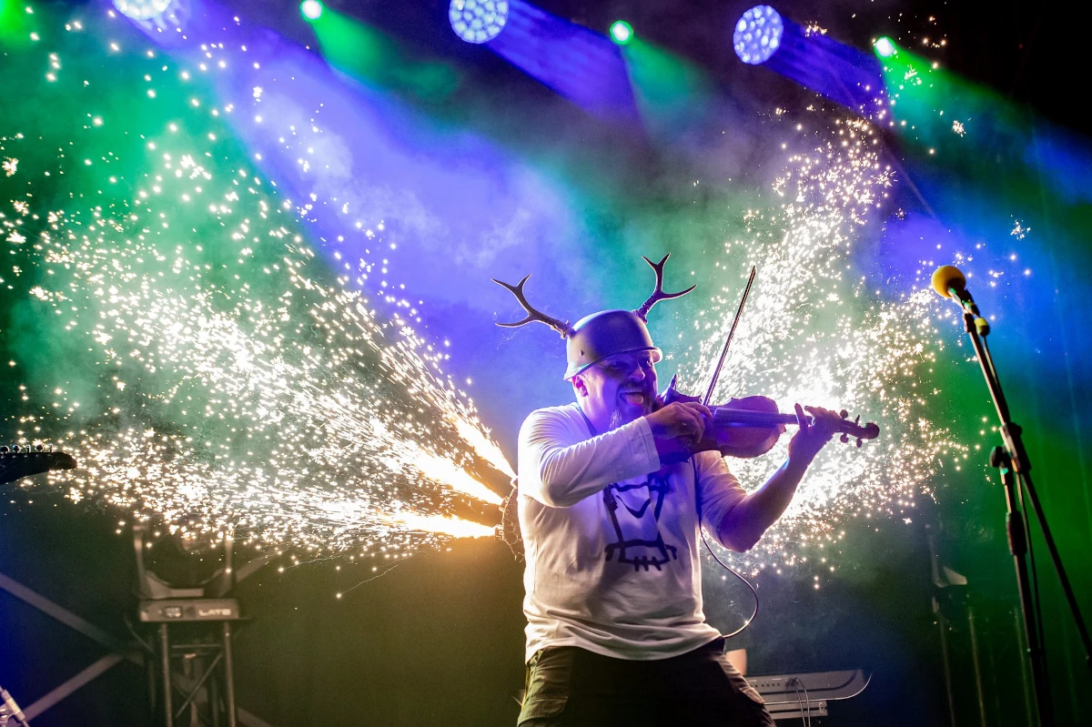 Koncert na scenie Pyrkonu z muzykiem grającym na skrzypcach w świetle reflektorów i efektów scenicznych