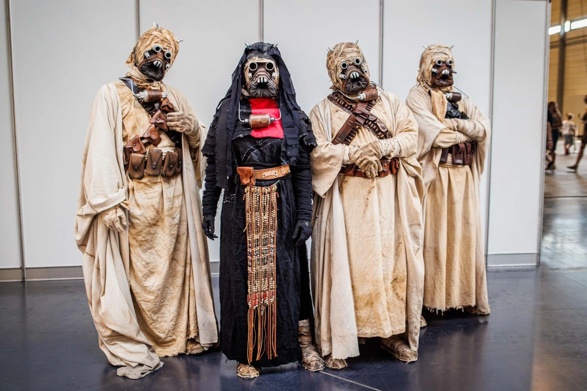 Grupa cosplayerów w pustynnych kostiumach i maskach na terenie festiwalu fantastyki
