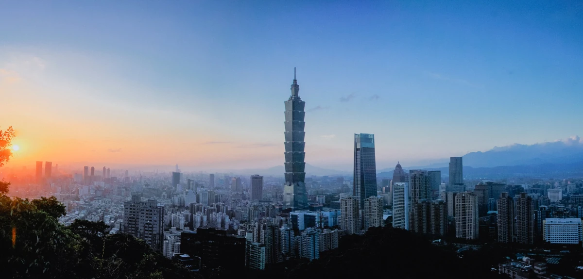Panorama Tajpej o zachodzie słońca z wieżowcem Taipei 101 na tle gór.