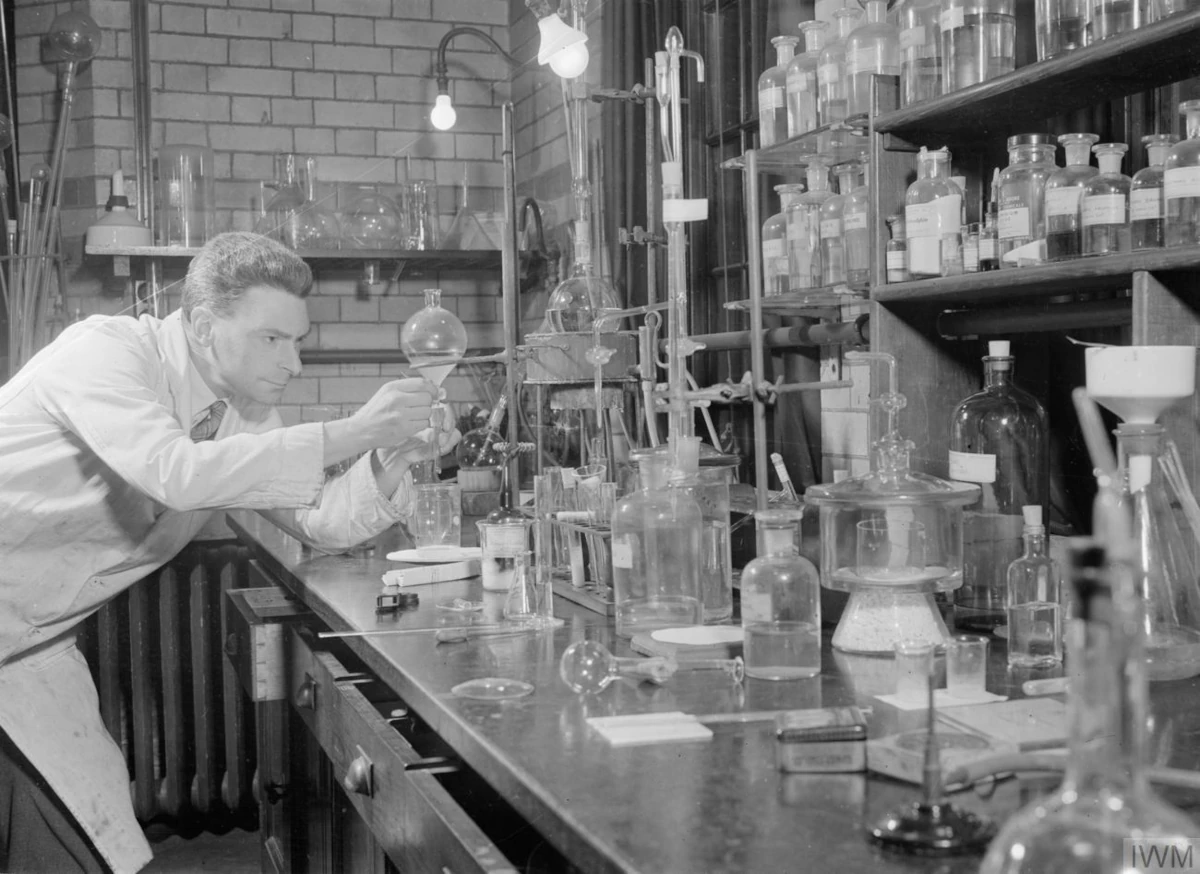 Wilson Baker przy stole laboratoryjnym zastawionym szklanymi naczyniami i aparaturą