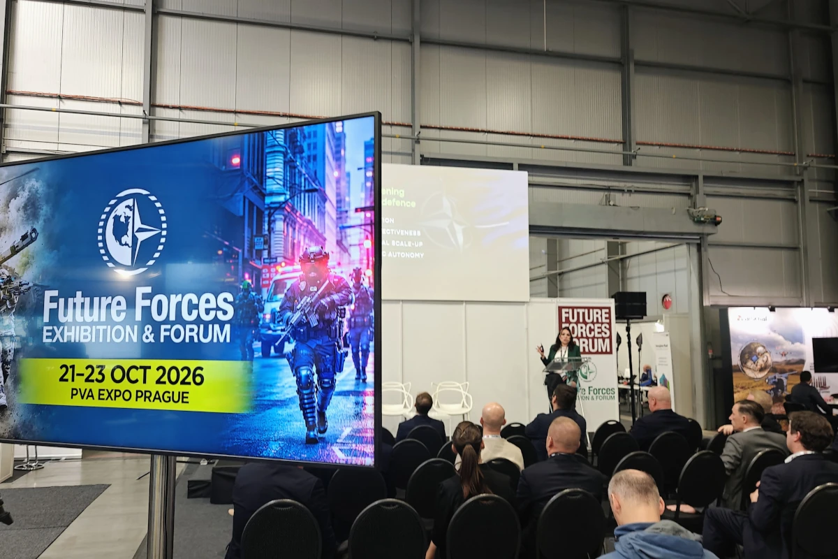 Ekran z nazwą i datami Future Forces 2026, a za nim prelegentka przy mównicy i publiczność w hali PVA EXPO PRAHA.